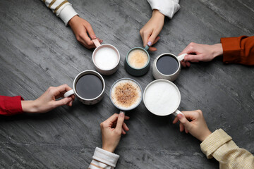 Fototapeta na wymiar People holding different cups with aromatic hot coffee at grey table, top view