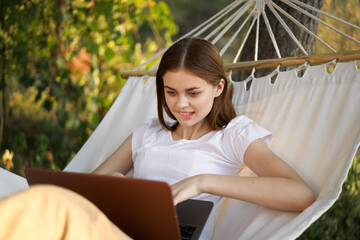 women outdoors lies in a hammock with a laptop freelance internet