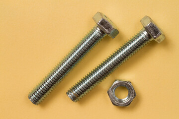 Metal bolts with nut on a yellow background.