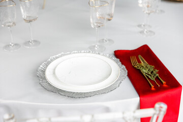Beautiful festive table setting. A luxurious dining set with cutlery, napkin, dishes and covered with a tablecloth in the restaurant. silver plates and crystal glasses. A plate with a marble pattern.