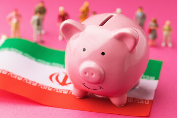 Piggy bank, Iranian flag and plastic toy men on a colored background, concept on the theme of Iranian population income