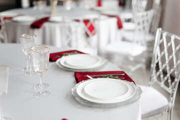 Beautiful festive table setting with napkins of different colors. A luxurious dining set with cutlery, napkin, dishes and covered with a tablecloth in the restaurant. Gold plates and crystal glasses. 