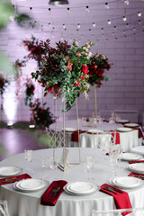 Canned round tables in the white hall. Wedding decorations made of flowers on the tables. the concept of the holiday.