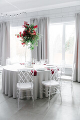 Canned round tables in the white hall. Wedding decorations made of flowers on the tables. the concept of the holiday.