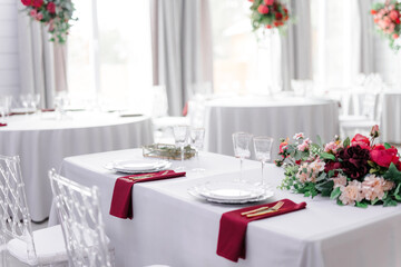 Beautiful festive table setting with napkins of different colors. A luxurious dining set with cutlery, napkin, dishes and covered with a tablecloth in the restaurant. Gold plates and crystal glasses. 