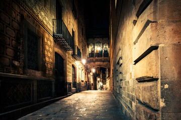 Fototapeta na wymiar Gothic quarter at night. Empty alleyways in Barcelona. Bridge between buildings in Barri Gothic quarter of Barcelona, Catalonia, Spain