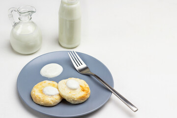 Cottage cheese pancakes with yogurt and fork on gray plate.