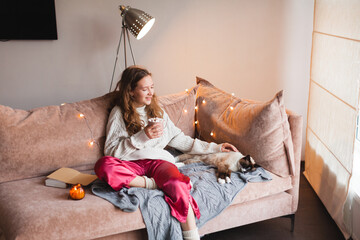 Young woman with dog drinking warm coffee at home