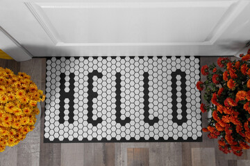 Stylish door mat with word Hello and beautiful flowers, flat lay