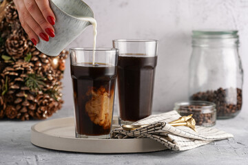 Pouring milk into a tall glass with cold coffee making frappe - iced cappuccino