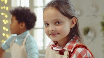 Portrait of pretty little girl in apron posing for camera on culinary masterclass