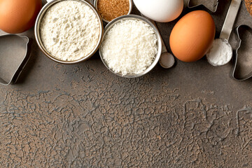 Ingredients for coconut cookies or sweet pastries on a culinary background. Eggs, coconut chips, flour, sugar and salt on a dark table. Top view	