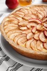 Tasty apple pie on white striped tablecloth, closeup