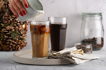 Pouring milk into a tall glass with cold coffee making frappe - iced cappuccino