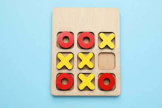 Tic tac toe set on light blue background, top view