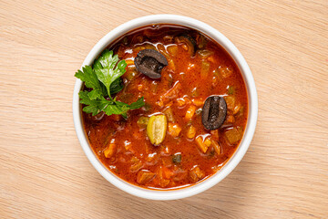Spicy solyanka soup topped with pork sausages, cucumber and lemon.