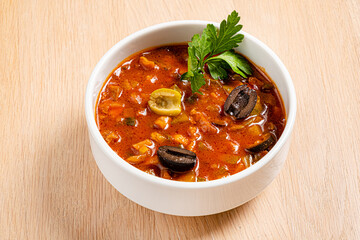 Spicy solyanka soup topped with pork sausages, cucumber and lemon.