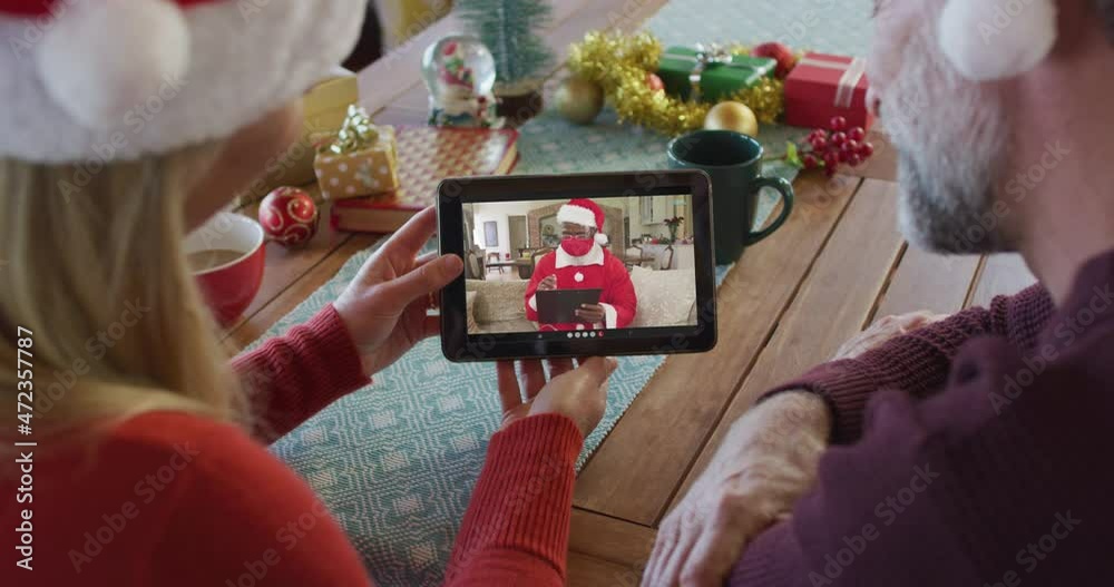 Canvas Prints Caucasian couple with santa hats using tablet for christmas video call with santa on screen