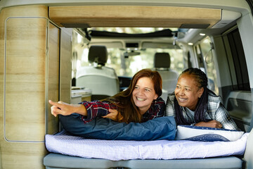 Diverse traveling women relaxing on bed in van © Gabriel Trujillo