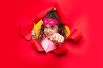 Powerful superhero girl tearing red paper background