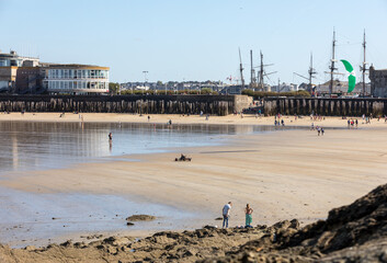 Naklejka premium Romantic walk of people before sunset on the picturesque beach of Saint Malo. Brittany, France