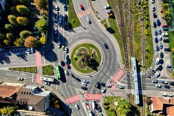 Lanes or lines of traffic in a roundabout on a main road, next to a railway line. Aerial top down view from drone in an urban area