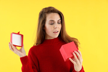 Attractive woman with gift box on yellow background