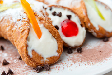 Cannoli siciliani, deliziosi dessert tipici della cucina Italiana farciti con crema di ricotta, frutta candita e gocce di cioccolato 