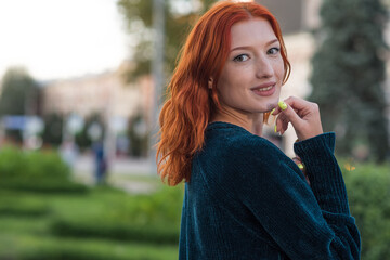 Portrait of a young, beautiful and attractive redhead Caucasian girl with freckles. Girl posing walking through the city.