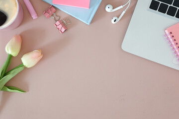 Top view, female workspace with computer laptop, notebook and pink tulips.