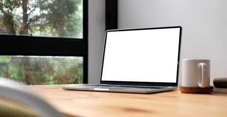 Fototapeta premium Computer laptop and coffee cup on wooden table. Blank screen for your advertising text.