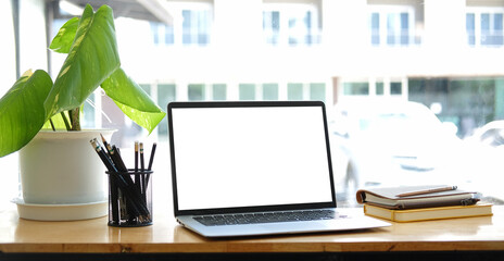Close up computer laptop with white screen on wood table in modern office..