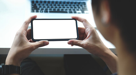 View over businessman shoulder holding smart phone. Blank screen for your advertising text.