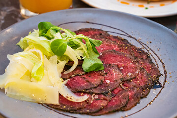 Carpaccio on a plate of vegetables and lemon. Italian cuisine. 