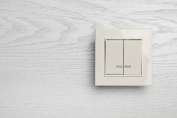 Modern light switch on white wooden background. Space for text