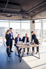 Business, technology and office concept - happy business team with laptop computers, documents and coffee. Meeting before the start of the working day to discuss a business plan
