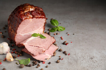 Delicious ham with spices, garlic and basil on grey table, space for text