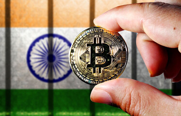 Hold the physical version of Bitcoin (the new virtual currency) and the Indian flag. Indian cryptocurrency and blockchain technology investor concept map 