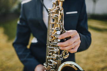 Obraz premium Stylish man, musician, saxophonist in a suit plays the saxophone.
