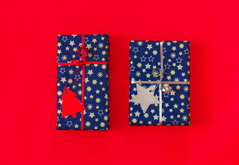 close up two gift boxes in blue paper with silver and red decoration for packaging on a red background
