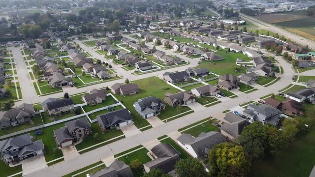 Aerial view of newer residential neighborhood in western Wisconsin. Symmetrical lines of larger homes and yards. Perfectly landscaped properties. Sunny sky and lake in corner.