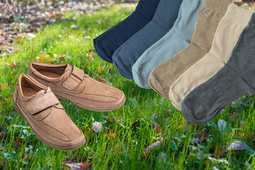 Beige men's boots and multi-colored socks on the background of a young lawn