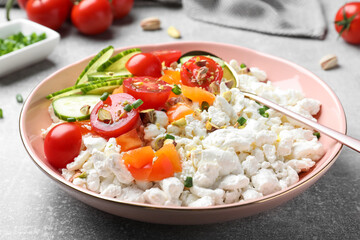 Delicious cottage cheese with vegetables served for breakfast on light grey table, closeup