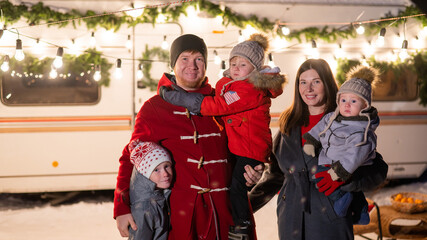 Happy large family celebrates christmas in nature and holds sparklers. Parents with three sons travels in a mobile home.