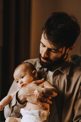 Stylish Caucasian bearded father carrying newborn baby on shoulder. Male man parent holding child...