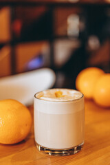 Transparent cup of coffee with milk and cream. Raf coffee with citrus peel on the table in a cafe