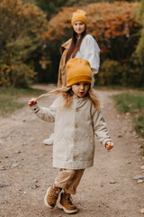 Young happy and smiling mom with her little daughter in arms hugging and kissing spending a weekend on a walk in autumn park. selective focus, noise effect, Autumnal mood