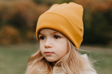 portrait of a little cute girl walking in the autumn park