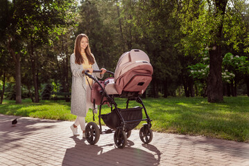 Full length body size photo young mother smiling walking in city park with baby carriage wearing...