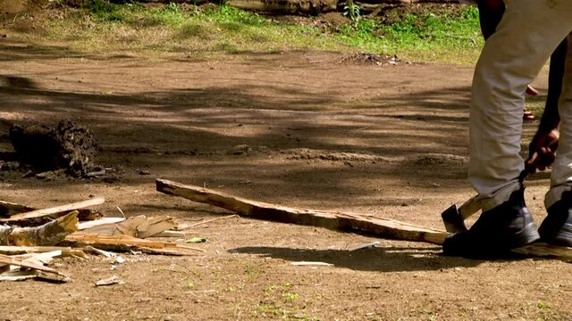 Young boy chopping firewood with axe.